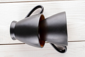 Two black ceramic tea cups on a wooden table, close-up, top view.