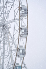 The snow-covered rim of the Ferris ring with viewing booths. Fragment. Snowfall. Copy space.