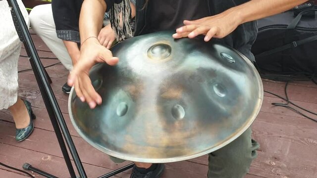 Man plays hanging drum or steel drum, modern steel musical instrument in the street. Music for relaxation and meditation. Close-up. Ethnic