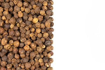 Lot of whole spicy black pepper isolated on white background filling half of frame flatlay