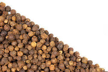 Lot of whole spicy black pepper isolated on white background filling half of frame diagonally flatlay