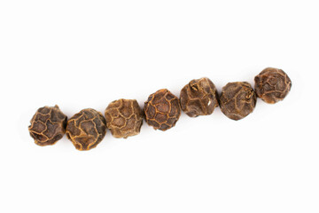 Group of seven whole spicy black pepper isolated on white background in row