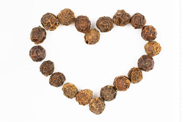 Lot of whole spicy black pepper isolated on white background making a heart shape