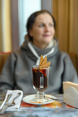 A glass of hot mulled wine in a cafe. Nearby there are cutlery on a napkin