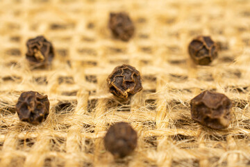 Group of seven whole spicy black pepper on natural sackcloth