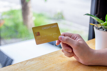 Women holding a yellow gold credit card to shop online, credit cards can accumulate points to use points for online shopping, credit cards to use installments.