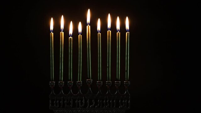Close up of burning menorah with candles for Hanukkah in the dark. Jewish holiday.