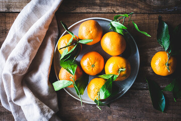 mandarinas en un plato sobre una mesa de madera envejecida, vista superior