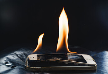burning broken smartphone on a black background. 