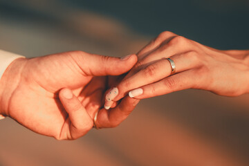 Wedding. Hands of man and woman on dark background on warm soft sunlight. New family is born. High quality photo