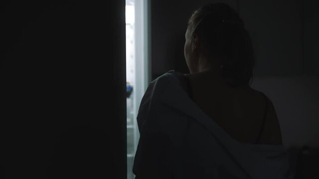 Woman is looking for food in refrigerator at night. Night hunger.