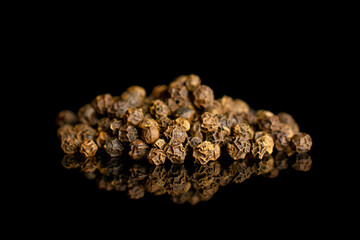 Lot of whole spicy black pepper isolated on black glass in small group