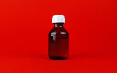 Small glass bottle with liquid medicine on red background