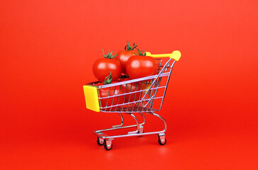 Red tomatoes in a shopping trolley on a red background