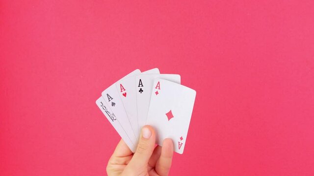 Five of a kind Poker Game cards in gambler hand falling money bills pink background. Lucky combination Aces and Joker revealing.Online gambling casino gaming Winner success bets concept Entertainment