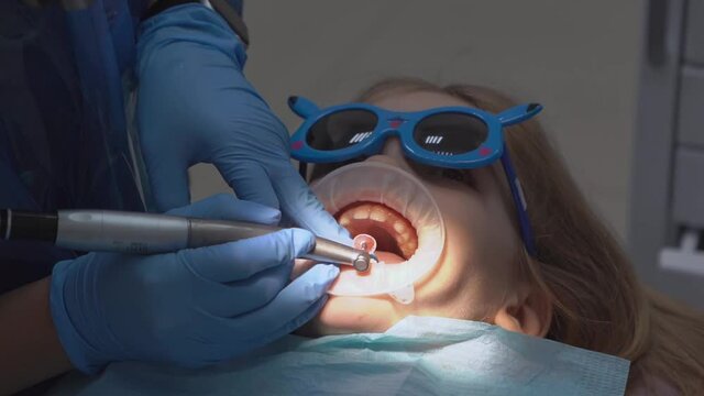 little girl with oral dilator at dentist's appointment. polishing of teeth