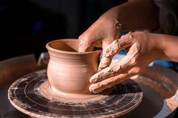 Potter master woman sculptor works with clay on a Potter's wheel and at the table with the tools. Close-up.