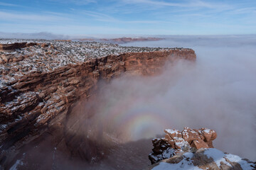 USA, Utah. Edge of canyon filled with encroaching fog and a rainbow, Island in the Sky, Canyonlands National Park.