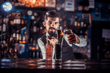 Charming barman is pouring a drink at the bar counter