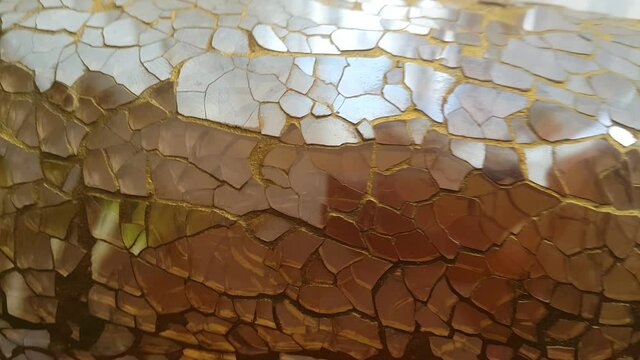 A decorative jar vase made of golden glass fragments reflects light with an elegant shimmer, creating a luxurious, artistic, and warm atmosphere suitable for modern interior visuals.