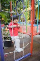 Obraz premium Little boy climbing rope on outdoor playground.