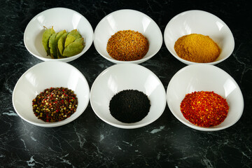 A set of spices in white cups on a black .