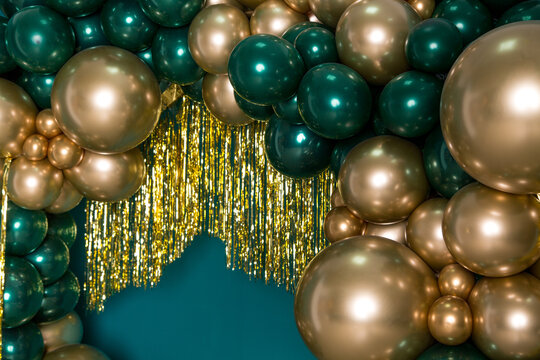 Arch of dark green and gold balloons on a green background