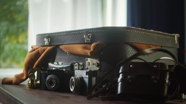 Old cameras composition. Antique photo equipment collection. Close-up of vintage old-fashioned camera on table, suitcase and compass for travelling. 