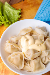 Dumplings in a white plate with salad on a wooden background.