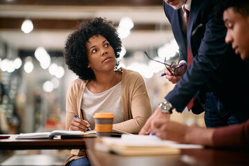 African American mid adult woman learns with help of professor at university library.