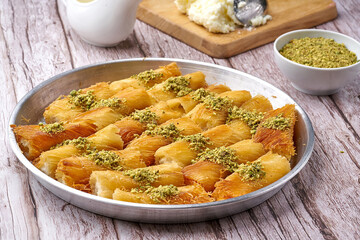Arabian Traditional Desserts rolls - Cream and cheeses with pistachio flavor and nuts topping on gray background