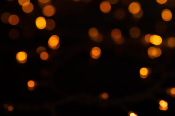 Fototapeta premium Defocused bokeh lights on black background, an abstract naturally blurred backdrop for Christmas eve or birthday party. Festive light texture. Yellow and red garland in blur. Overlay effect for design