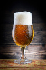 Cold beer with foam on wooden table