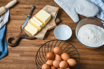 Cook cuts butter on the table with ingredients.