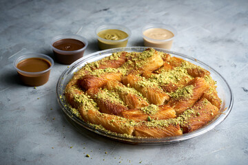 Arabian Traditional Desserts rolls - Cream and cheeses with pistachio flavor and nuts topping on gray background