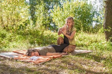 Girl masseuse demonstrates refreshing massaging methods in the sunlight.