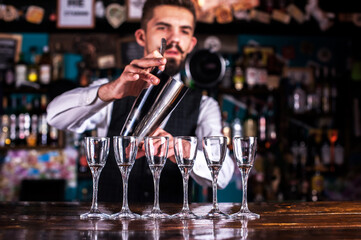 Bearded bartender intensely finishes his creation at bar