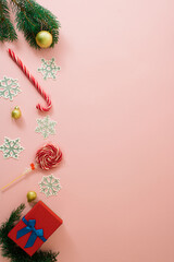 Christmas and new year creative scene, with happy purple pink background.  Xmas decoration concept with copy space. Lollipop stick Candy Cane with snowflake and red gift box, baubles and pine branch.
