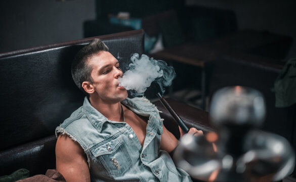 A man of European appearance exhales smoke in the hookah bar.