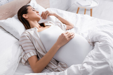 high angle view of pregnant woman sleeping in bed.