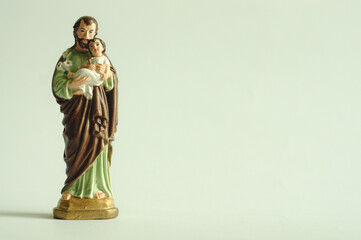 Figurka św. Józefa trzymającego małego Jezusa na jasnym tle.