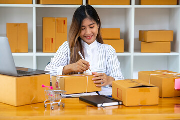 Fototapeta na wymiar Starting Small business entrepreneur SME freelance,Portrait young woman working at home office, BOX,smartphone,laptop, online, marketing, packaging, delivery, SME, e-commerce concept