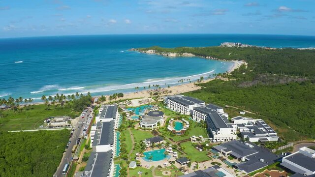 Beautiful sea coast with sandy palm beach. Great view of Dreams Macao Beach Punta Cana, Dominican Republic. Luxury resort with swimming pools, aerial view. Green peninsula in the blue sea.