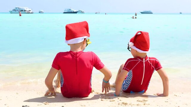 Christmas boys in Santa Claus hat play on the trop