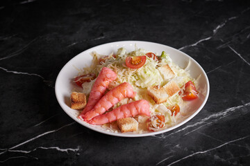 asian salad with meat and seafood, shrimp, plate close-up on a dark background