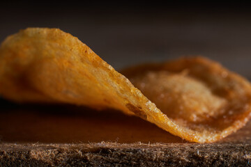 macro photo of chips on a wooden table, a slice of fried potatoes, beer snacks, blurred background