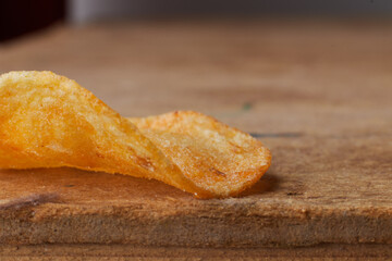 macro photo of chips on a wooden table, a slice of fried potatoes, beer snacks, blurred background
