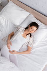 top view of young pregnant woman sleeping in bed.