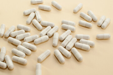 white medical capsules scattered on beige background