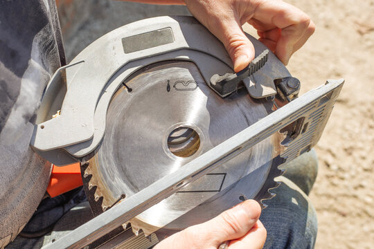 man replaces the saw blade of an electric miter saw for woodworking. Repair and maintenance of power tools